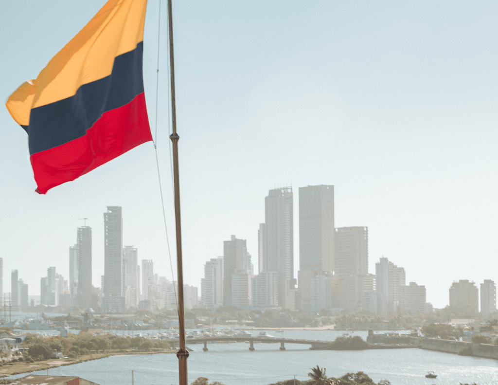 Colombian flag in focus with a city behind it